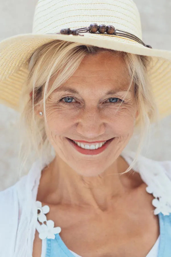 Menopause-Treatment A beautiful, smiling older woman with blonde hair and a sunhat, living with menopause in Newfoundland.
